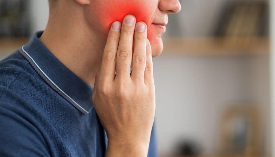 Man holding jaw with wisdom teeth pain